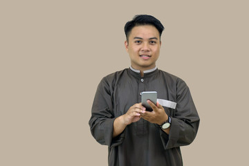 portrait of daytime Muslim youth posing in Muslim attire standing in front of the camera, looking attentive with a smile on the screen