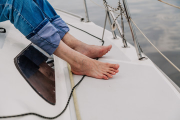 Bare feet stand on deck of  yacht