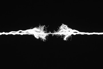 Tearing the rope in the middle of the frame on black background - obrazy, fototapety, plakaty