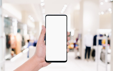Mockup image of man hand holding smart phone with blank white screen for your advertisement on blurred abstract background of men clothing fashion shop. Business shopping online concept.