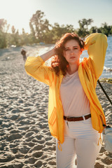 Beautiful plus size woman in yellow jacket on sandy shore