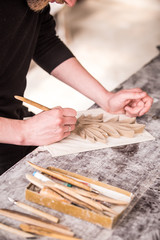 The sculptor creates a bas-relief. Plaster workshop. Close up. Selective focus.