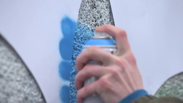 Graffiti artist in the street making art using spray paint and stencil. Stencil street art, urban culture