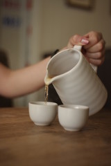 woman pouring milk from jug into cup