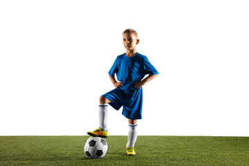 Young boy as a soccer or football player in sportwear standing with the ball like a winner, the best forward or goalkeeper on white background. Fit playing boy in action, movement, motion at game. © master1305