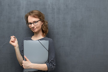 Portrait of girl with glasses holding folder and pen