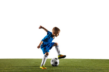 Obraz premium Young boy as a soccer or football player in sportwear making a feint or a kick with the ball for a goal on white studio background. Fit playing boy in action, movement, motion at game.