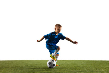 Obraz premium Young boy as a soccer or football player in sportwear making a feint or a kick with the ball for a goal on white studio background. Fit playing boy in action, movement, motion at game.