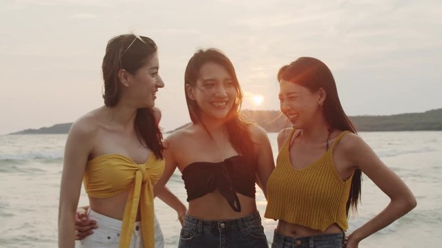 Group of Asian women talking together enjoy funny moment on beach, Beautiful female relax on beach near sea when sunset in evening. Woman travel on beach in summer concept. Slow motion shot.