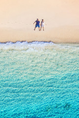 Aerial view of a people couple on the beach on Bali, Indonesia. Vacation and adventure. Beach and turquoise water. Top view from drone at beach, azure sea and relax couple. Travel and relax - image