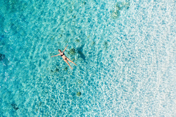 Aerial view of a girl on ocean on Bali, Indonesia. Vacation and adventure. Turquoise water. Top view from drone at ocean, azure watre and relax girl. Travel and relax - image