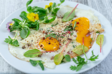 Plate of fried egg with bacon ancd melted cheese, on white plate, top view on vintage wooden background