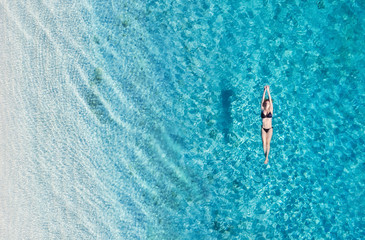 Aerial view of a girl on ocean on Bali, Indonesia. Vacation and adventure. Turquoise water. Top view from drone at ocean, azure watre and relax girl. Travel and relax - image