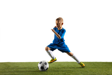 Obraz premium Young boy as a soccer or football player in sportwear making a feint or a kick with the ball for a goal on white studio background. Fit playing boy in action, movement, motion at game.