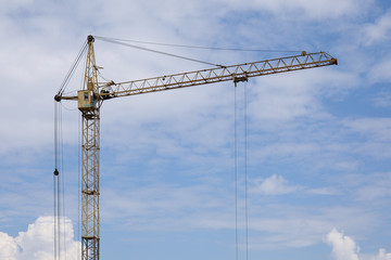 Industrial construction building crane against blue cloudy sky