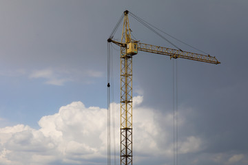 Industrial construction building crane against grey cloudy sky