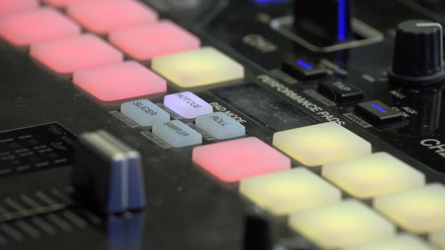 DJ beat maker pushing colourful buttons on the beat pad. Close up of mans fingers pressing buttons at music production studio