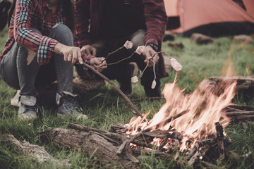 Fototapeta premium close up couple travel camping hands are roasting marshmallows over the fire, Great warm evening, camping concept.
