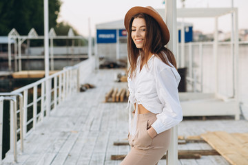 A happy stylish woman walks along the beachfront on a warm summer day in the sunset