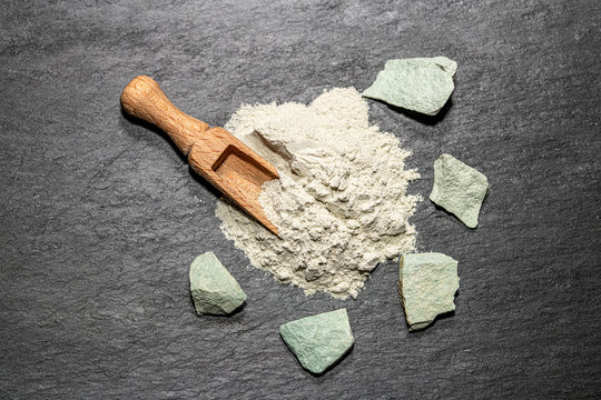 Zeolite natural  raw stones and powder on black stone  background.Selective focus
