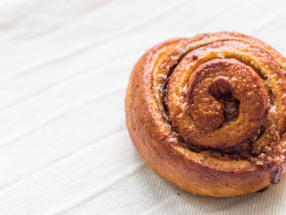 Fototapeta premium Confectionery baking. Sweet fresh soft roll bun with cinnamon on white background. Cinnabon closeup