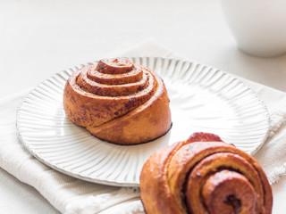 Confectionery baking. Sweet fresh soft roll bun with cinnamon on white background. Cinnabon closeup