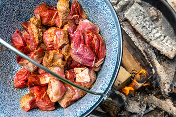 Frying the raw beef in a cauldron over an open wood fire to prepare the Hungarian cauldron goulash, food