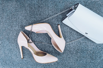 Beige high-heeled shoes and a white handbag