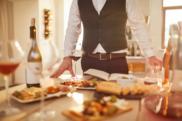 Mid section portrait of unrecognizable sommelier standing by table during wine tasting session,...