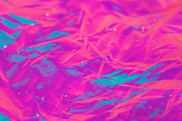 Abstract background of neon colours from crumpled gift paper and backlight
