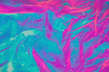 Abstract background of neon colours from crumpled gift paper and backlight