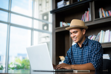 Young casual businessman using laptop, smartphone for working.