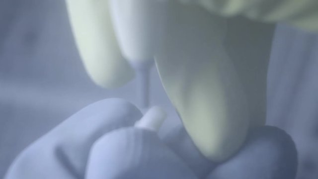 Dental technician polishing artificial ceramic teeth using sandblaster in the dental lab. Professional wearing gloves while holding fake teeth in hand and polishing it with sand blaster