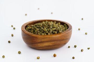 Dried green peppercorns in a wooden bowl. White background, high resolution
