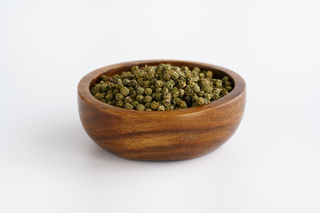 Dried green peppercorns in a wooden bowl. White background, high resolution