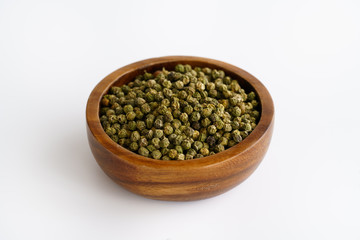 Dried green peppercorns in a wooden bowl. White background, high resolution