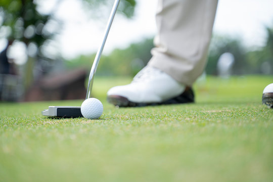Golf player at the putting green hitting ball. - Image