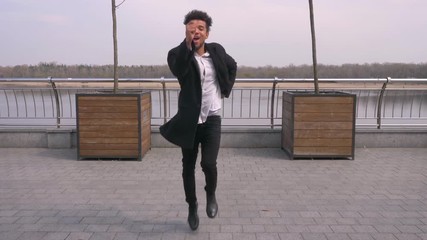 Closeup straight view portrait of young attractive african american businessman dancing and making shuffle moves looking at camera on the street in the urban city