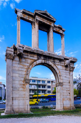 Athens, Attica / Greece. The Arch of Hadrian, most commonly known in Greek as Hadrian's Gate, is a monumental gateway resembling, in some respects, a Roman triumphal arch.  Sunny day, blue cloudy sky