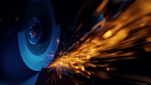 Close-up of welder grinding smooths steel and iron using modern equipment. Industrial production, locksmith industry concept. Sparks from grinding wheel.