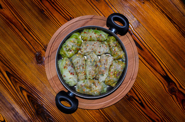 Cabbage Rolls, Dolma. Stuffed cabbage leaves with minced meat, rice, vegetables, herbs in plate. Isolated on rustic wooden table, cutting board, copy space for text. Top view. Sarma, golubtsy, golabki