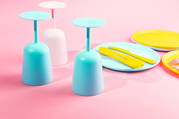 Bright colored plastic picnic utensils. Pink, yellow, blue colors in the bowl. Photo in hard light. Copy space