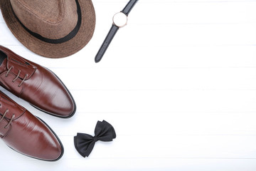 Male leather shoes with hat, wrist watch and bow tie on white background