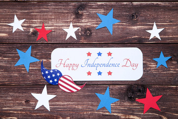 Text Happy Independence Day with paper stars and mustache on brown wooden table