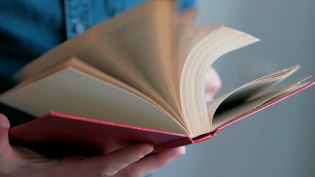 Close-up - Pages of the book are flipped. Looped. Man flips pages the book back and forth.