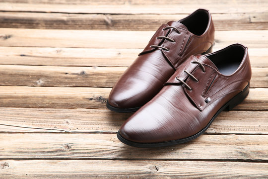 Male leather shoes on brown wooden table