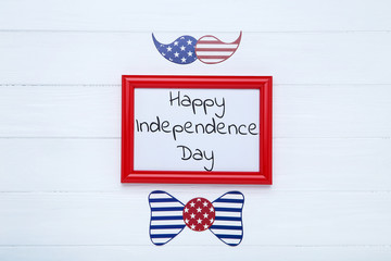 Text Happy Independence Day with paper bow tie and mustache on white wooden table