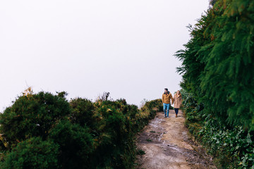 the couple in love hold hands and climb the dirt road to the mou