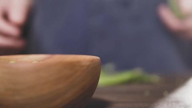 Farmer's hand throws wooden bowl of green peas on table, close-up, slow motion. Agricultural concept. Eco food.