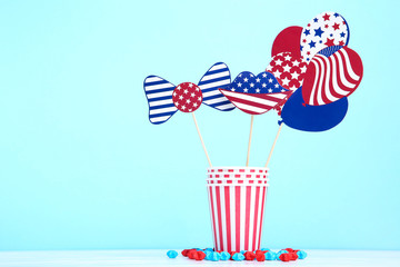 Paper cups with bow tie, lips and balloons in american flag on blue background